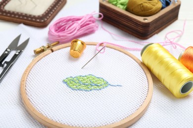 Embroidery and different sewing accessories on table, closeup