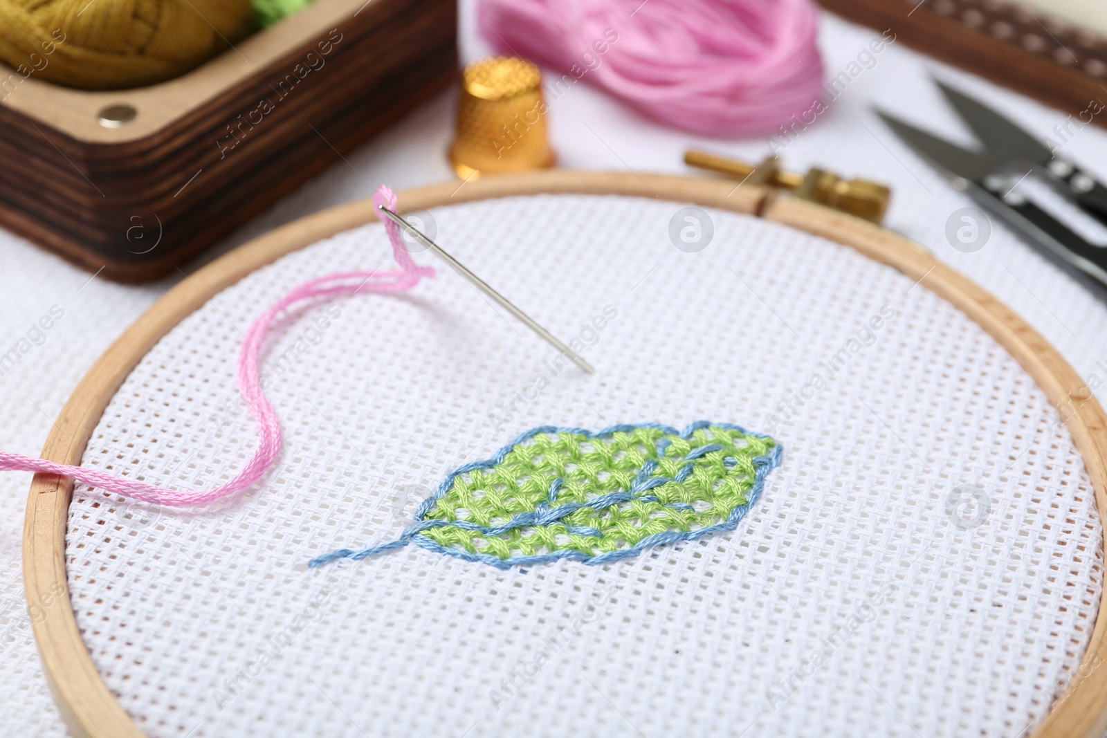 Photo of Embroidery and different sewing accessories on table, closeup