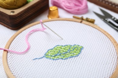 Embroidery and different sewing accessories on table, closeup