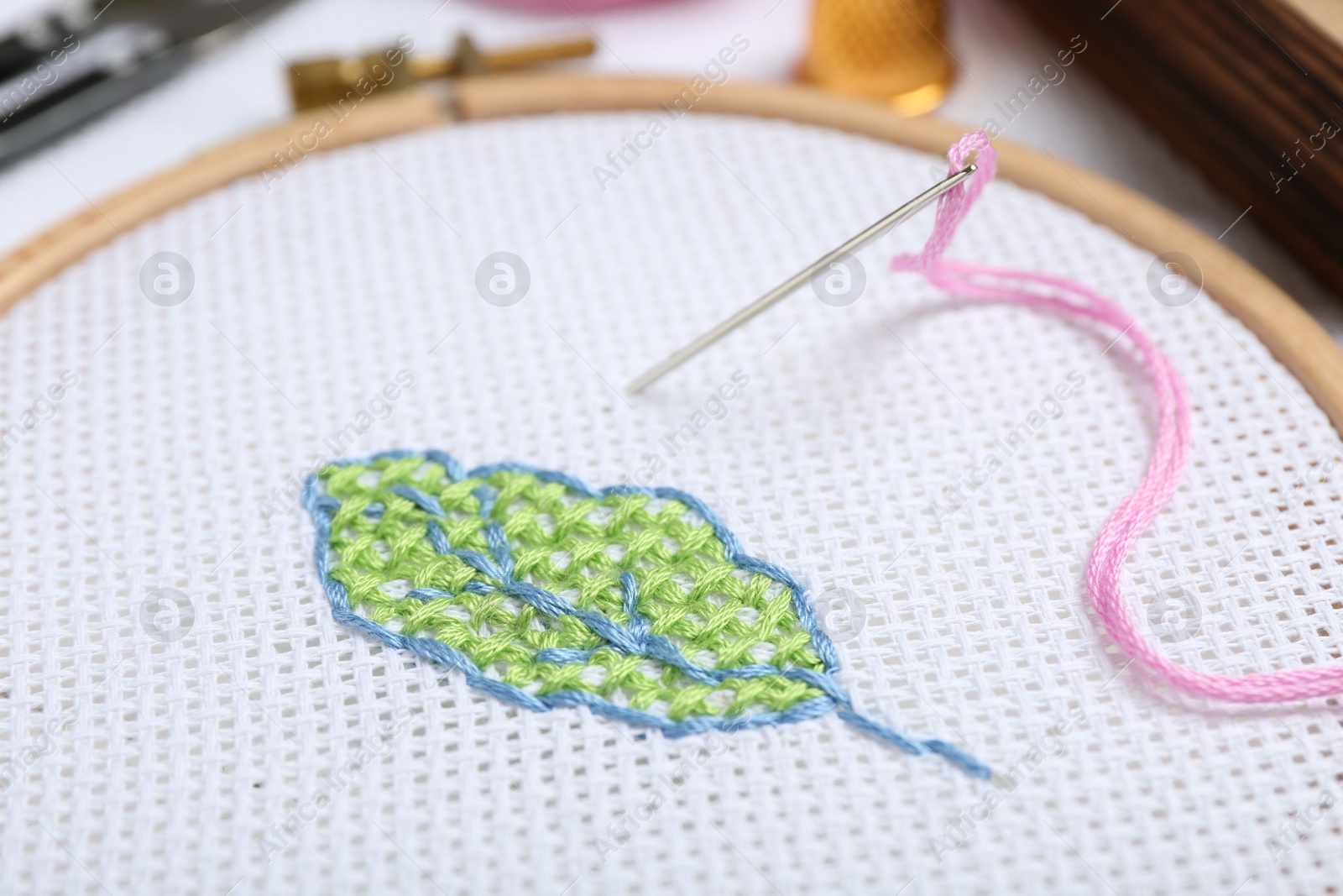 Photo of Canvas with embroidery in hoop on table, closeup