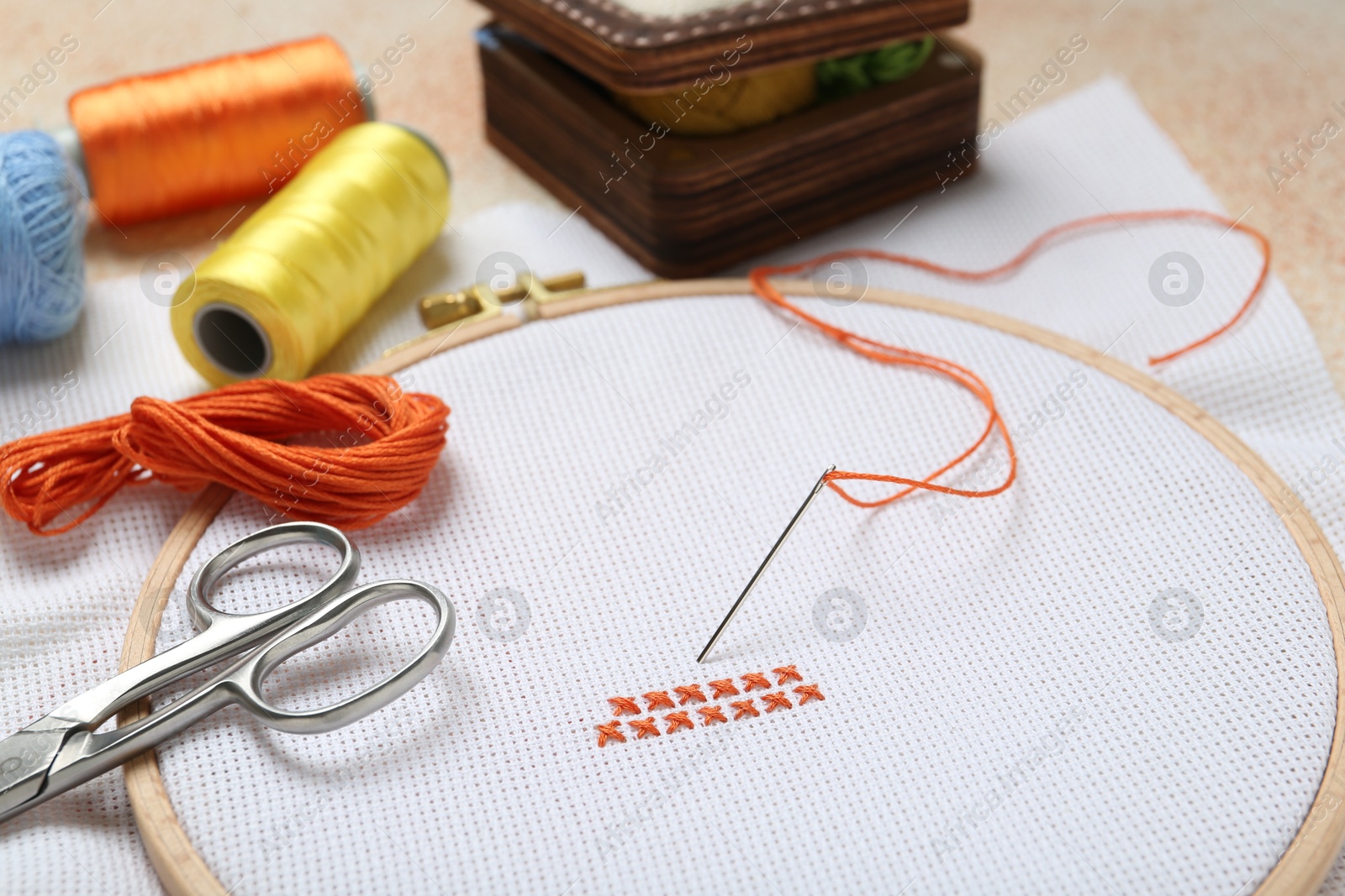 Photo of Embroidery and different sewing accessories on table, closeup