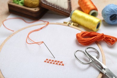 Photo of Embroidery and different sewing accessories on table, closeup