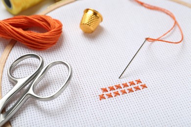 Photo of Embroidery and different sewing accessories on table, closeup