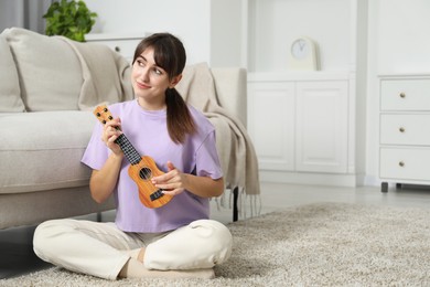 Photo of Woman playing ukulele on floor at home, space for text