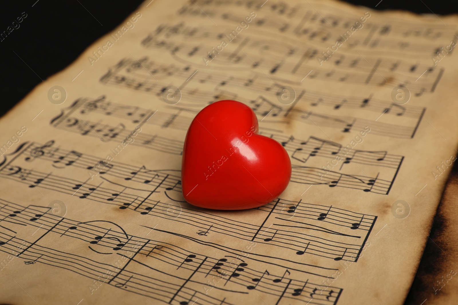 Photo of Heart figure and musical notes on black background, closeup