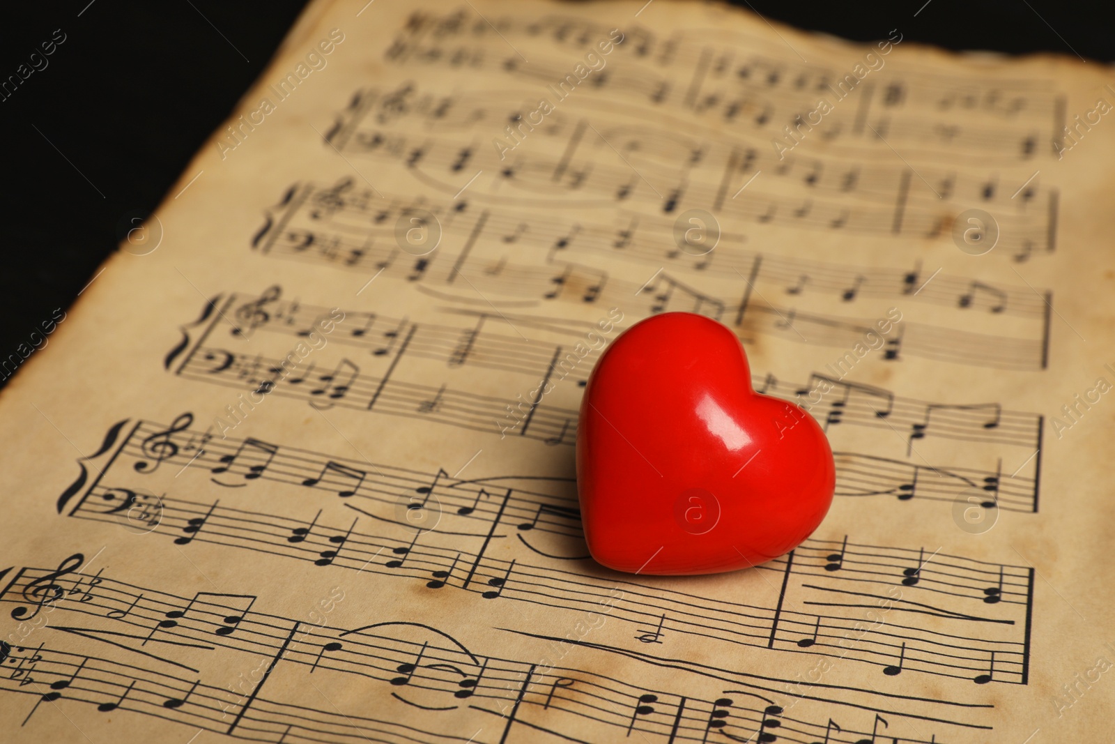 Photo of Heart figure and musical notes on black background, closeup