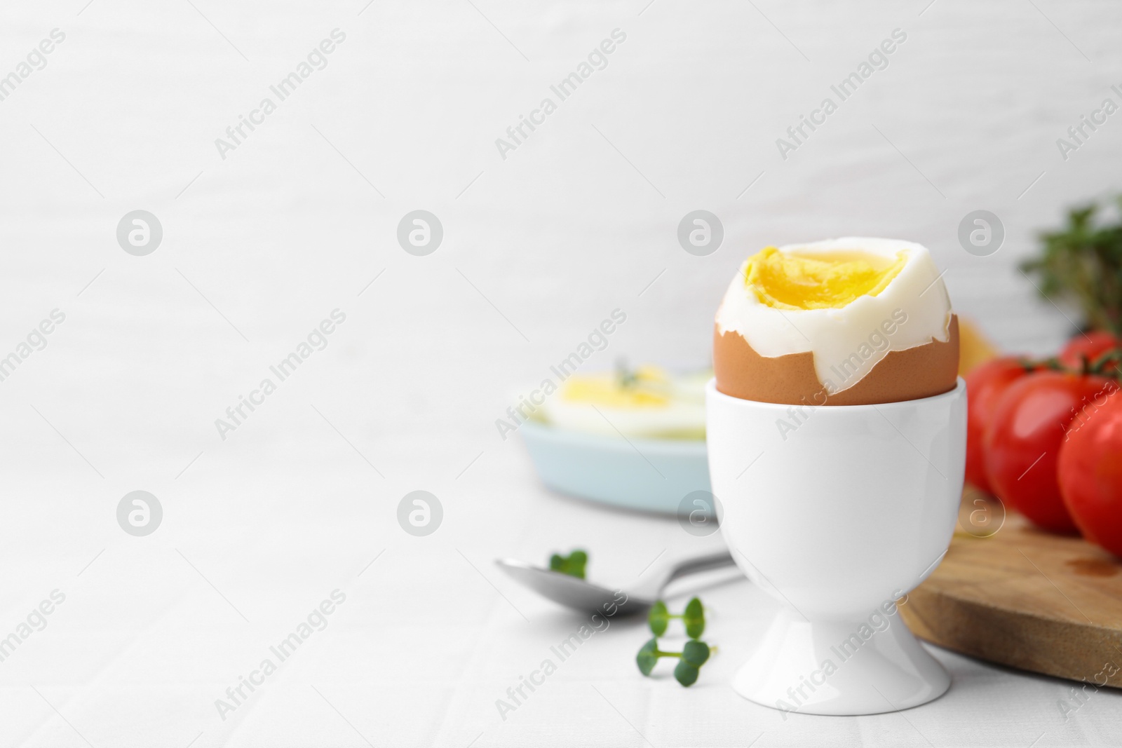 Photo of Soft boiled egg on white tiled table, closeup. Space for text