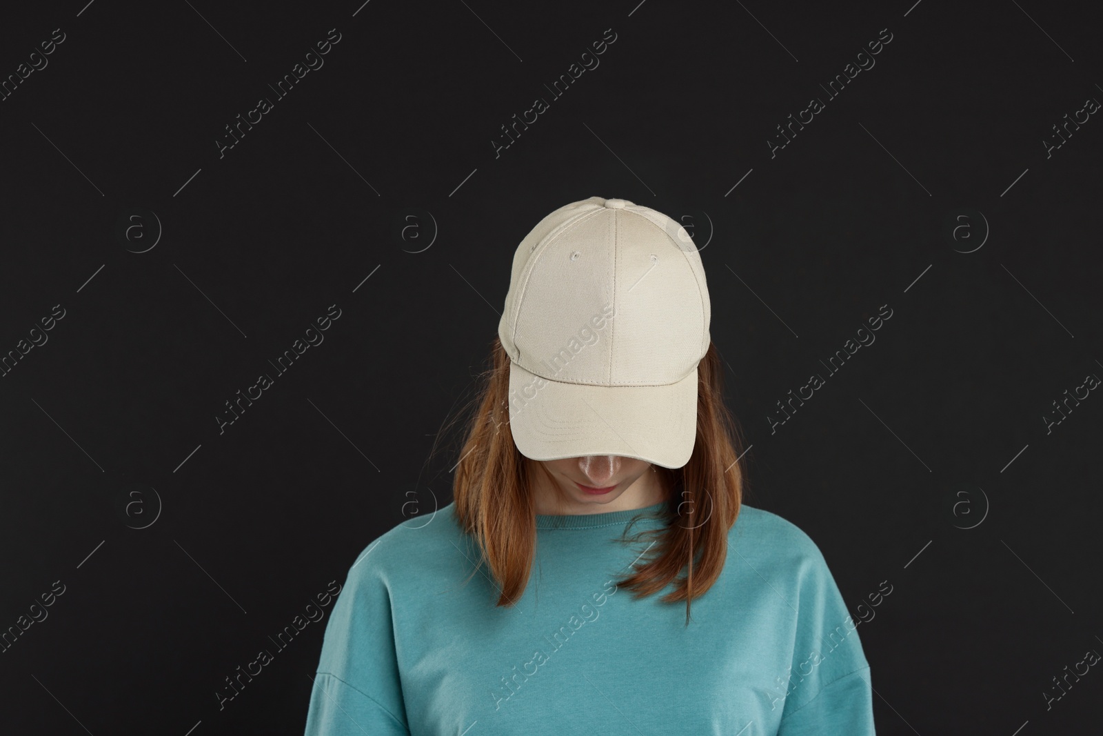 Photo of Woman in stylish baseball cap on black background. Mockup for design