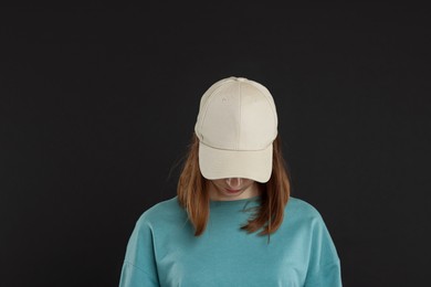 Photo of Woman in stylish baseball cap on black background. Mockup for design