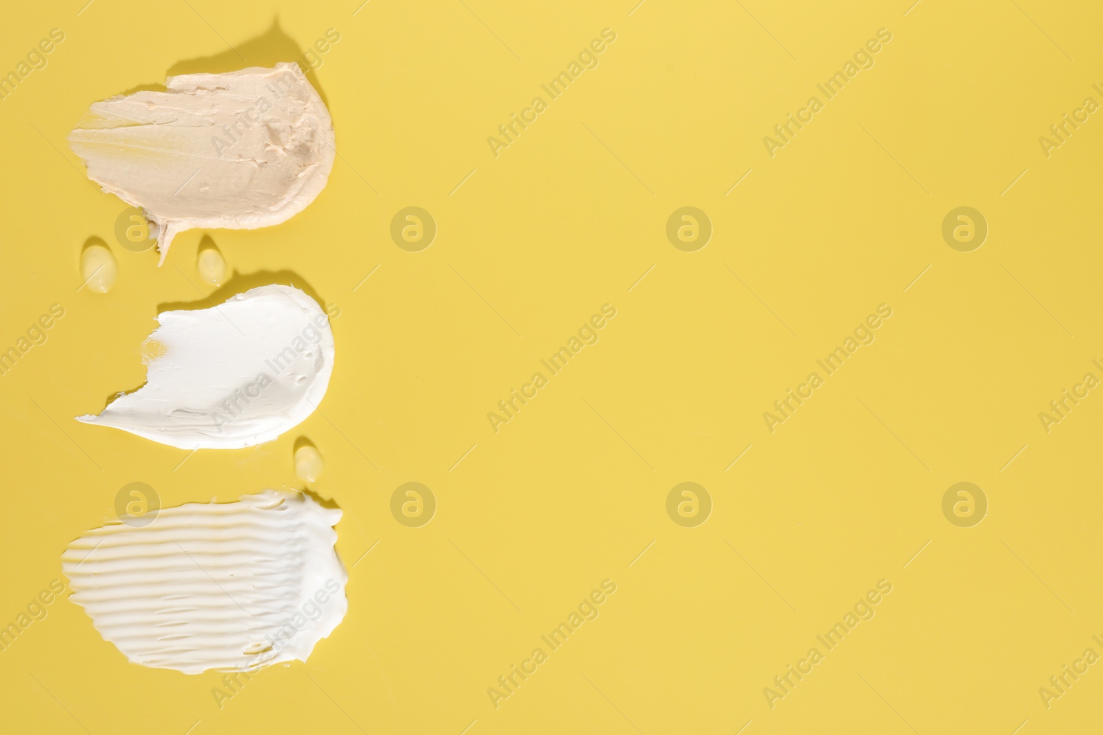 Photo of Samples of different cosmetic products on yellow background, flat lay. Space for text