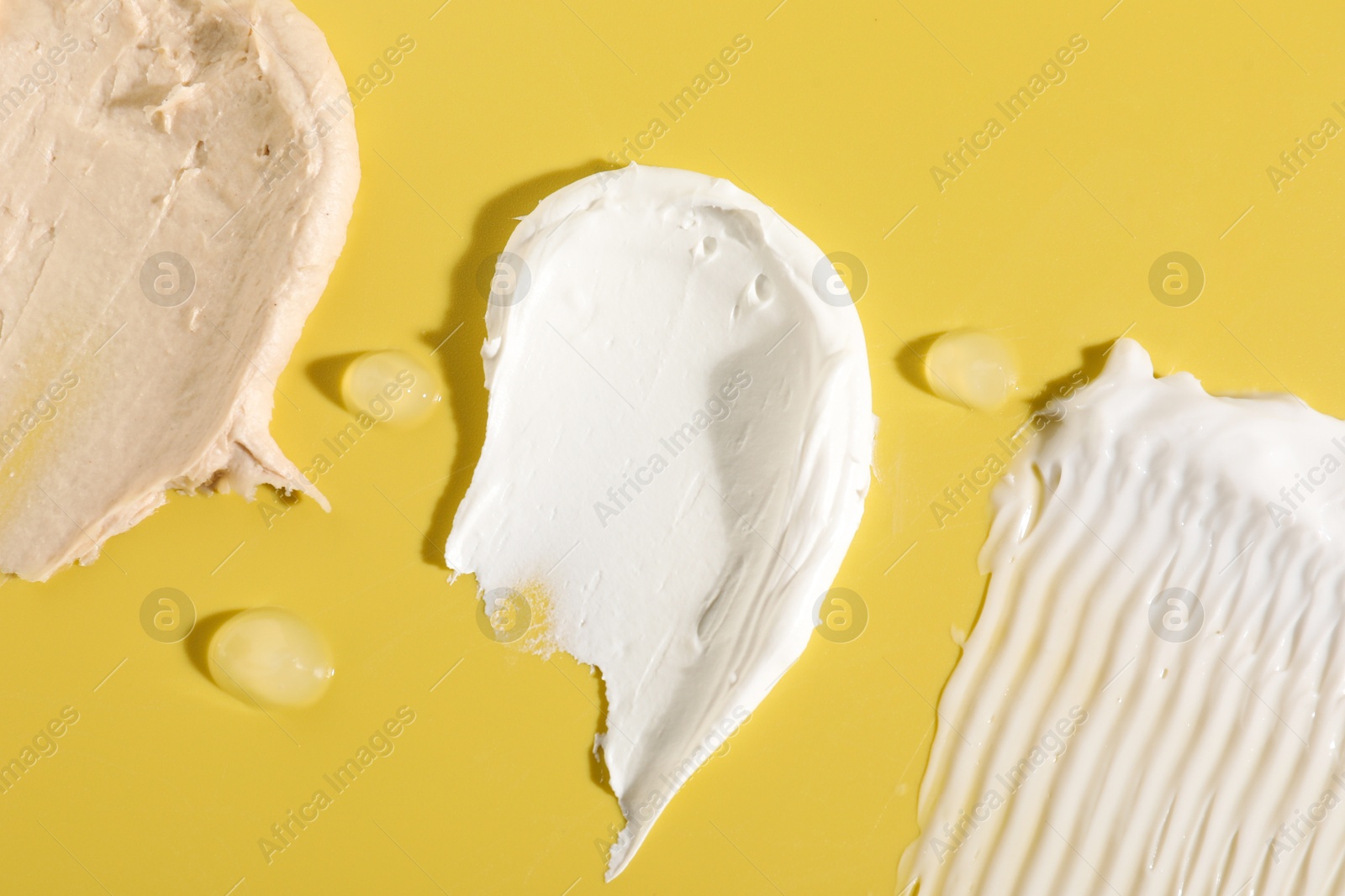 Photo of Samples of different cosmetic products on yellow background, flat lay