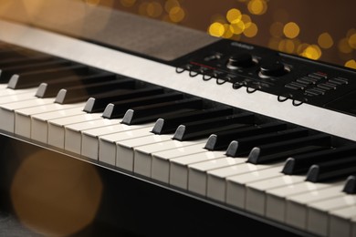 Photo of Piano against blurred lights, closeup. Bokeh effect