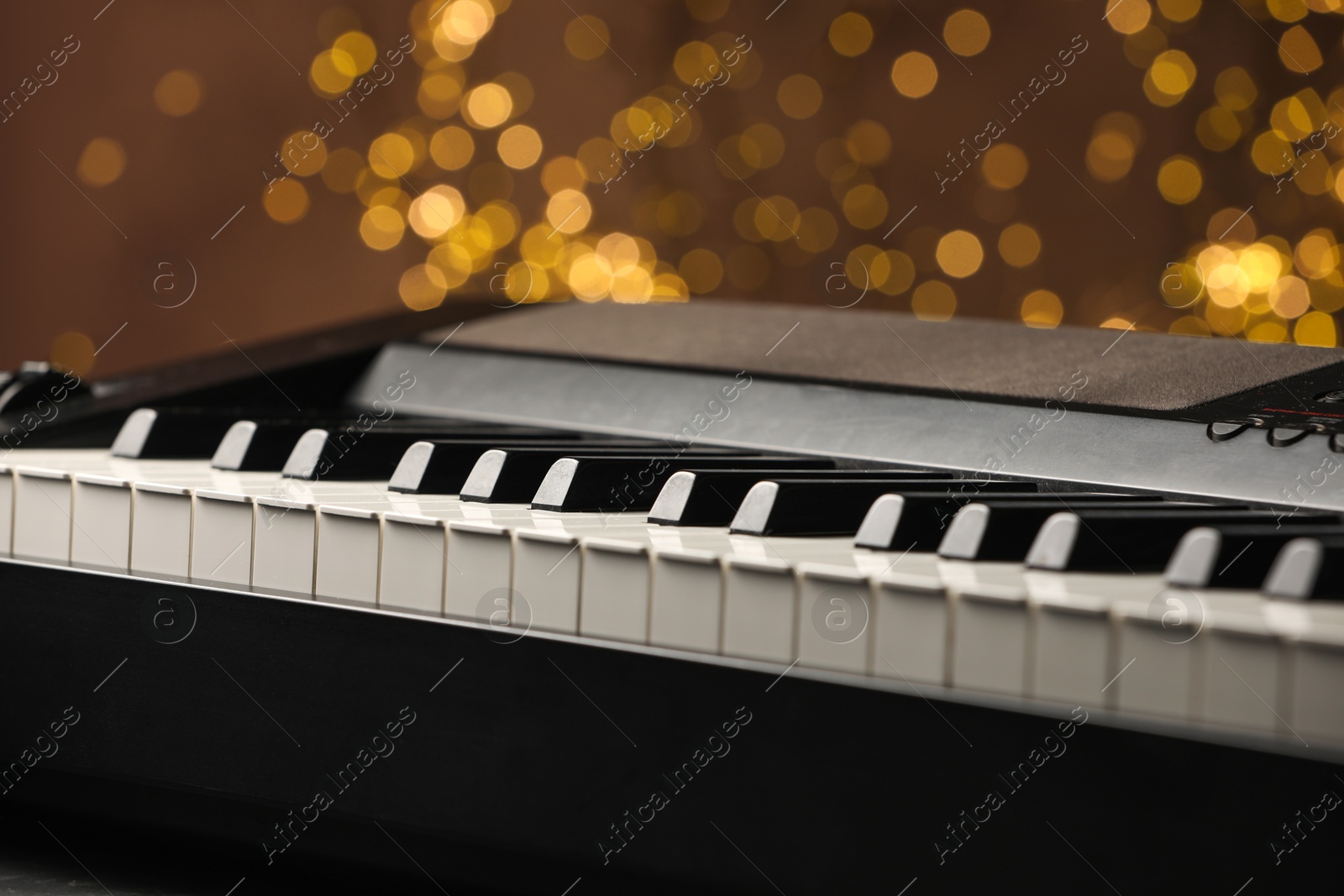 Photo of Piano against blurred lights, closeup. Bokeh effect