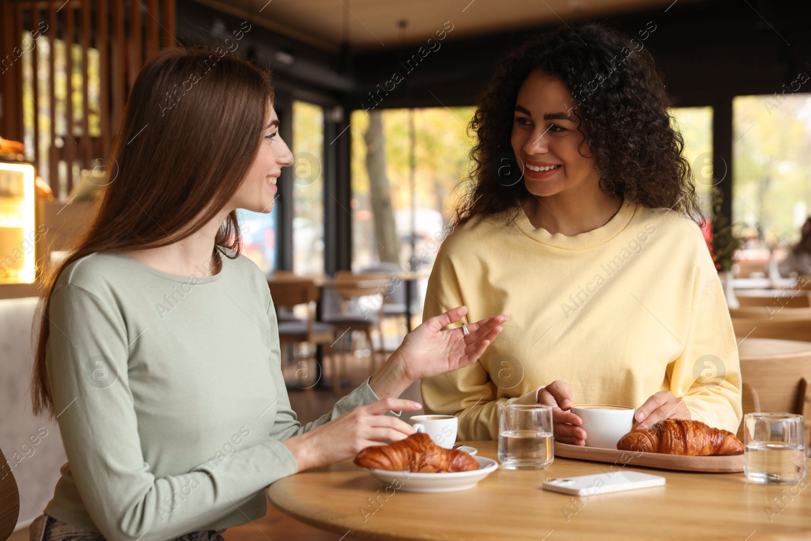 Photo of Happy women with coffee drinks chatting in cafe