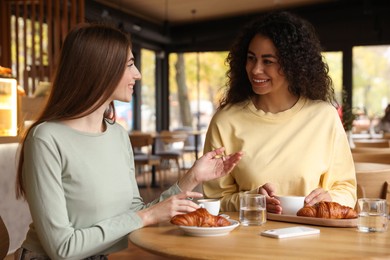 Photo of Happy women with coffee drinks chatting in cafe