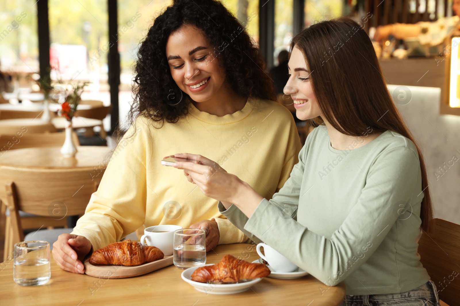 Photo of Woman taking picture of coffee drinks during meeting with her friends in cafe