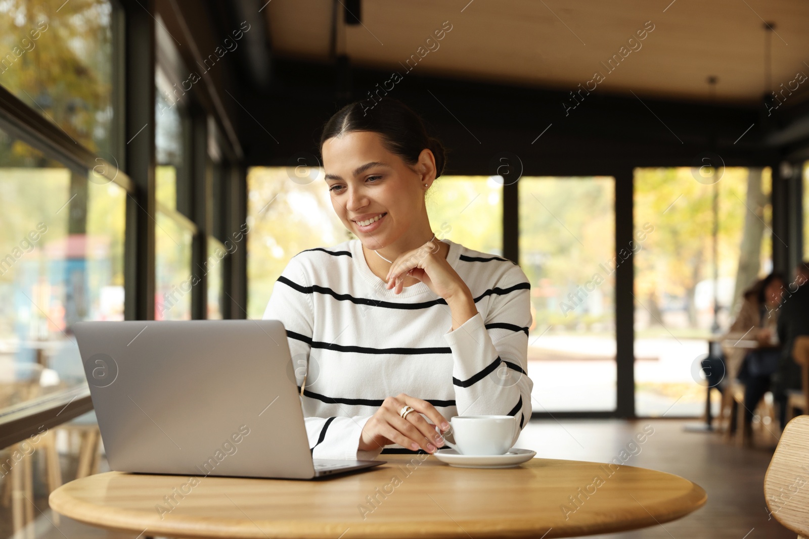 Photo of Woman working on laptop at table in cafe