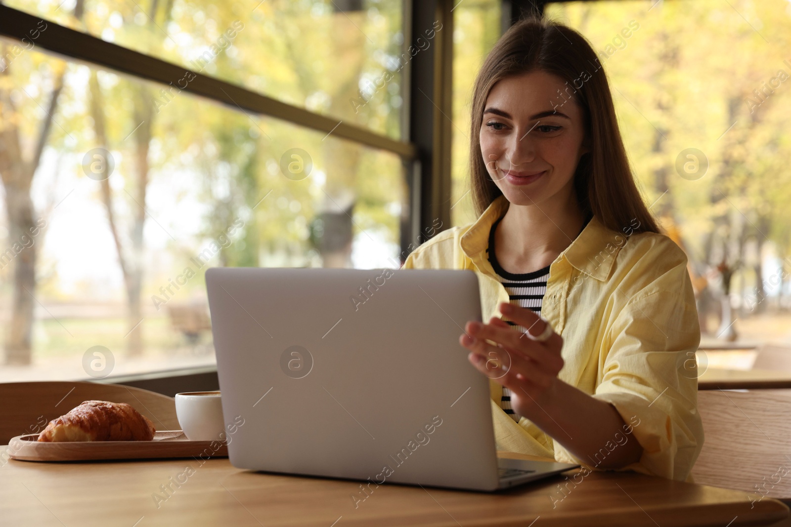 Photo of Woman working on laptop at table in cafe