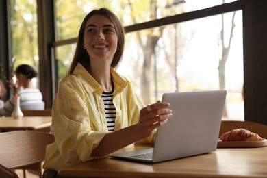 Photo of Woman working on laptop at table in cafe