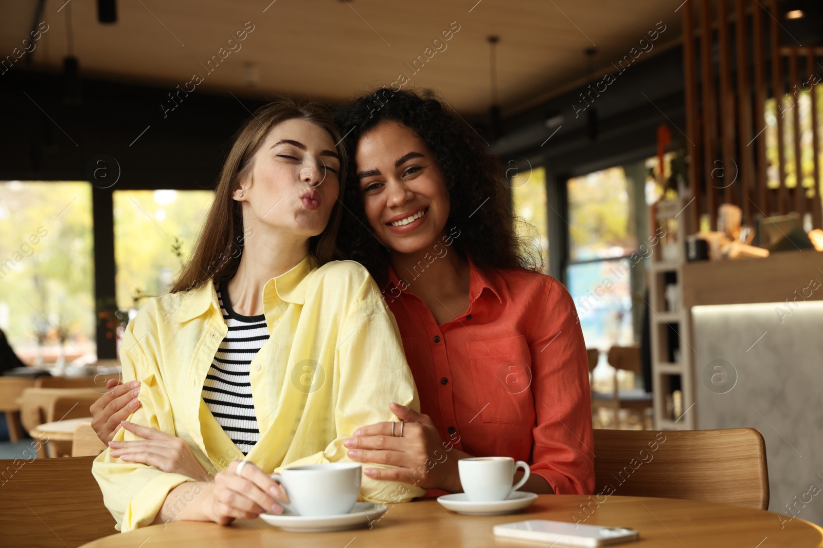 Photo of Happy women with coffee drinks at table in cafe