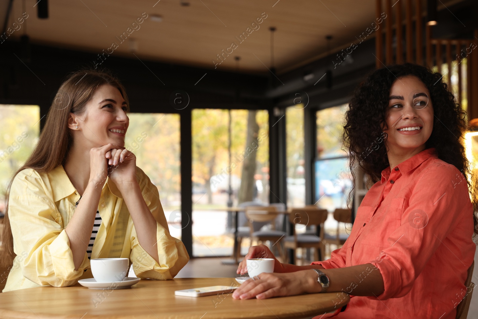 Photo of Happy women with coffee drinks chatting in cafe