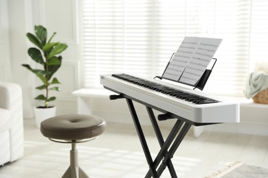 Photo of Synthesizer with music sheets and stool at home