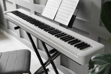 Photo of Synthesizer with music sheets at home, closeup