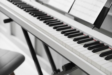 Photo of Synthesizer with music sheets at home, closeup