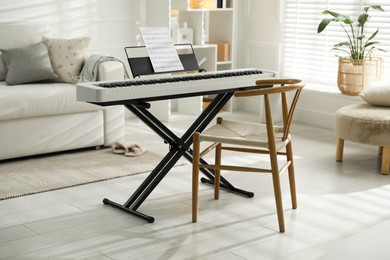 Photo of Synthesizer with music sheet and chair at home