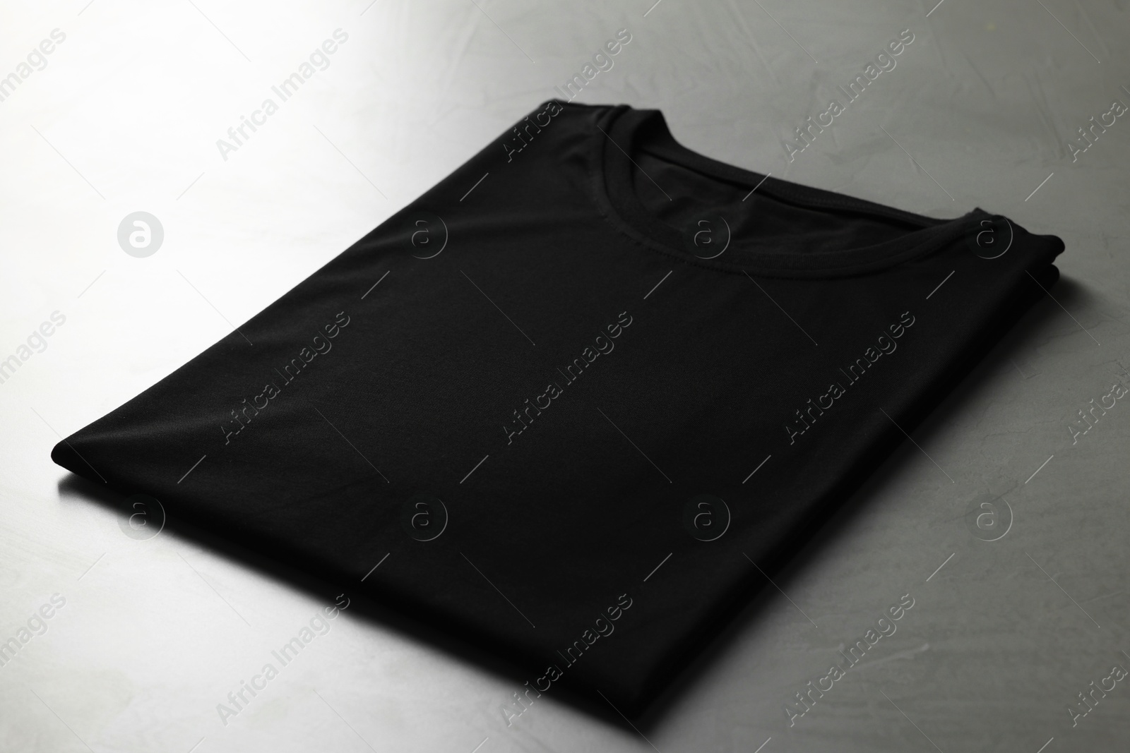 Photo of Blank black t-shirt on grey table, closeup. Mockup for design