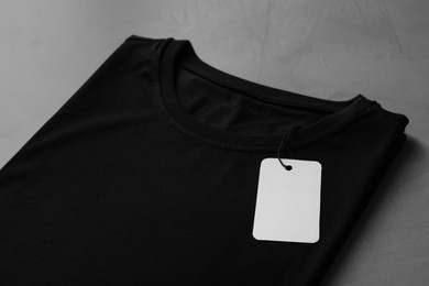 Photo of Blank black t-shirt on grey table, closeup. Mockup for design