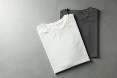 Photo of Different blank t-shirts on grey background, top view. Mockup for design