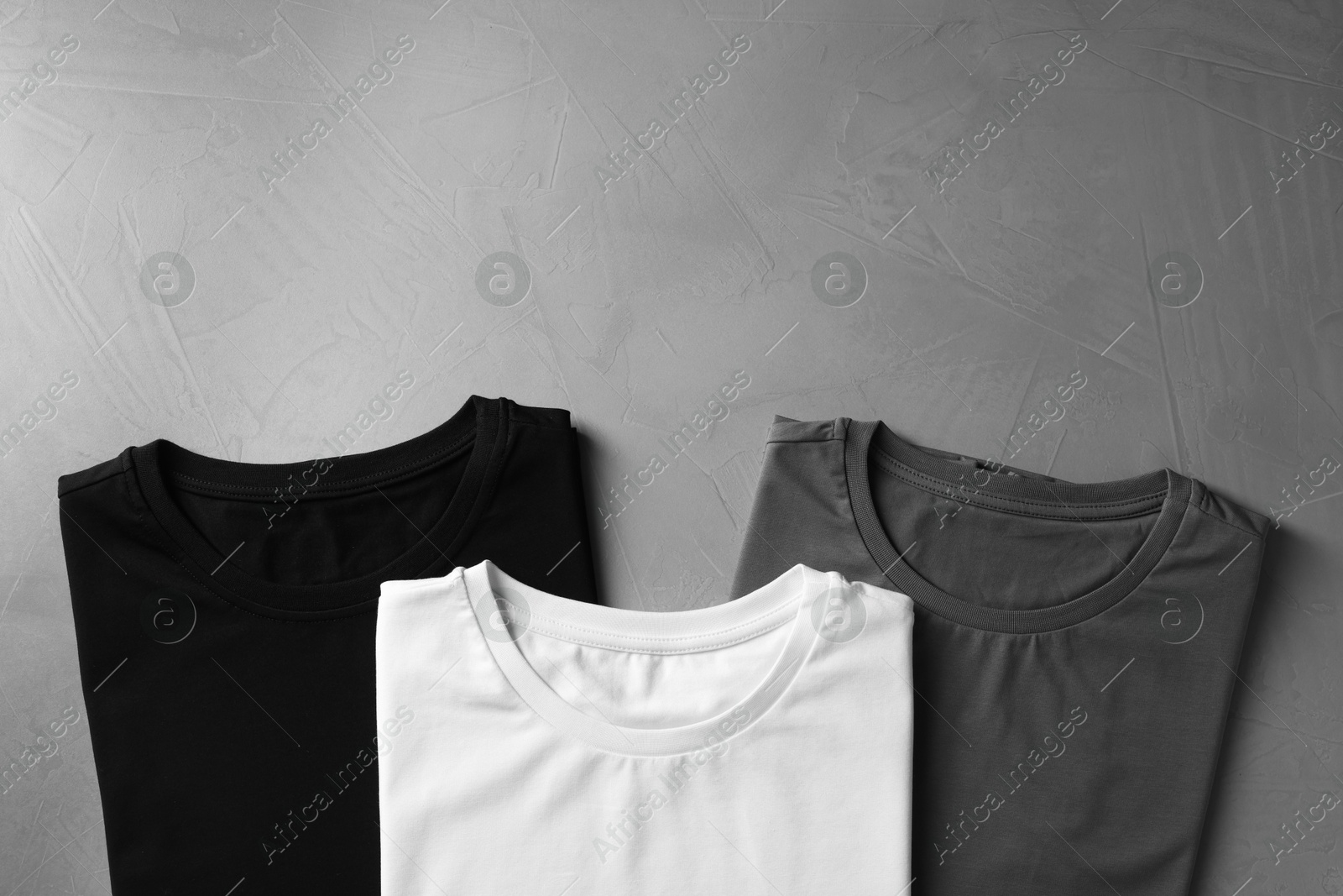 Photo of Different blank t-shirts on grey background, top view. Mockup for design