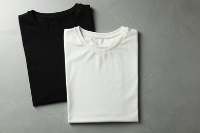 Photo of Different blank t-shirts on grey background, top view. Mockup for design