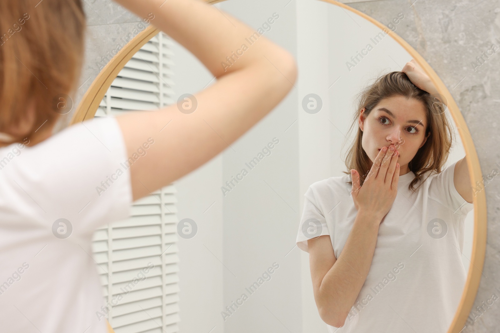 Photo of Girl with hair loss problem near mirror in bathroom