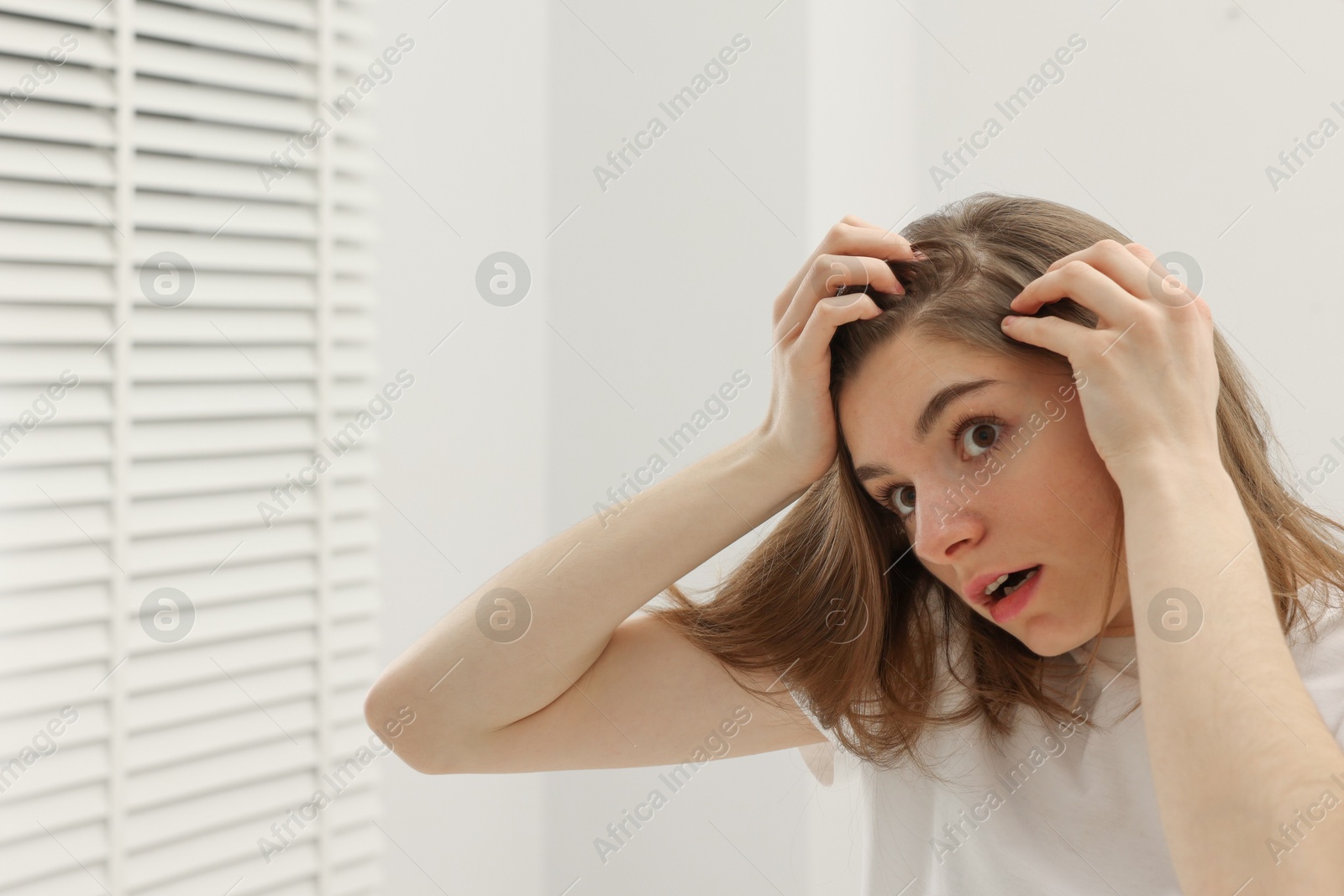 Photo of Girl with hair loss problem near mirror in bathroom, space for text