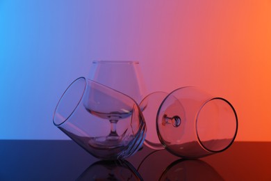 Photo of Empty glasses on table against color background