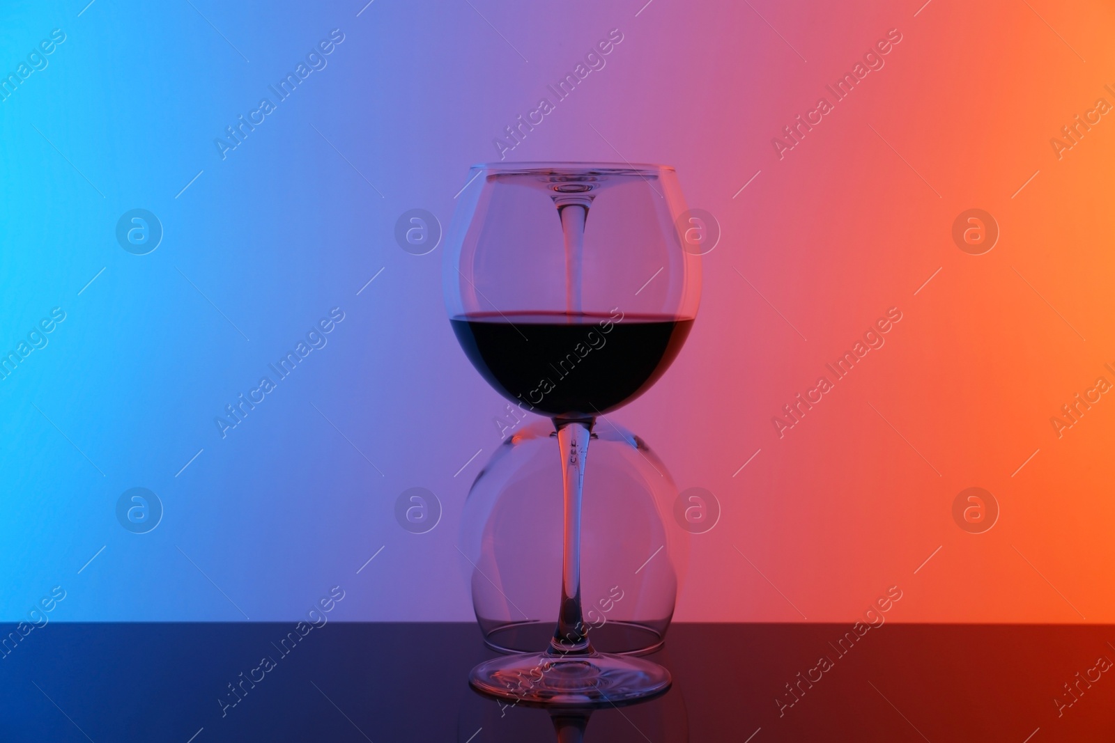 Photo of Wine glasses on table against color background