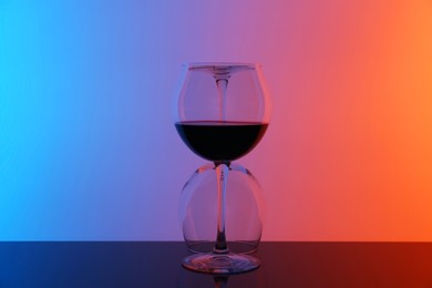 Photo of Wine glasses on table against color background