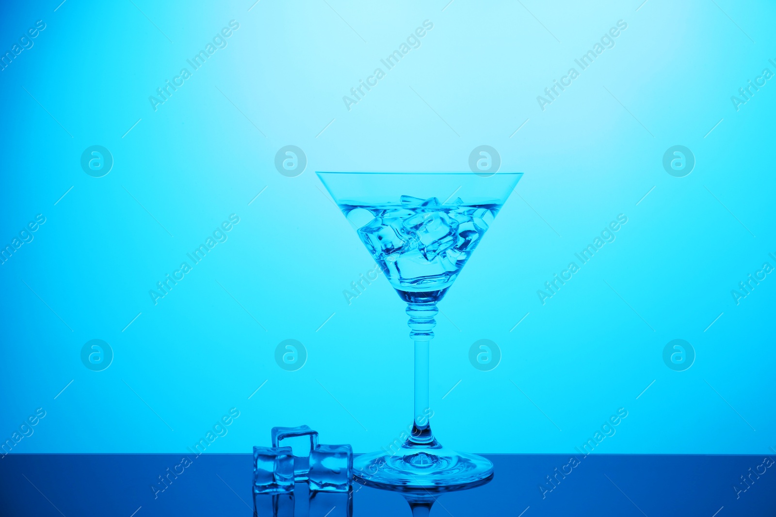 Photo of Cocktail glass with water and ice cubes on table, color tone effect