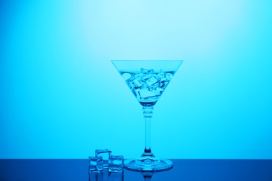 Photo of Cocktail glass with water and ice cubes on table, color tone effect