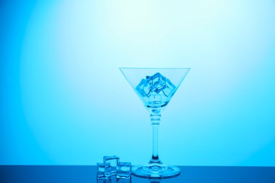 Photo of Cocktail glass with ice cubes on table, color tone effect