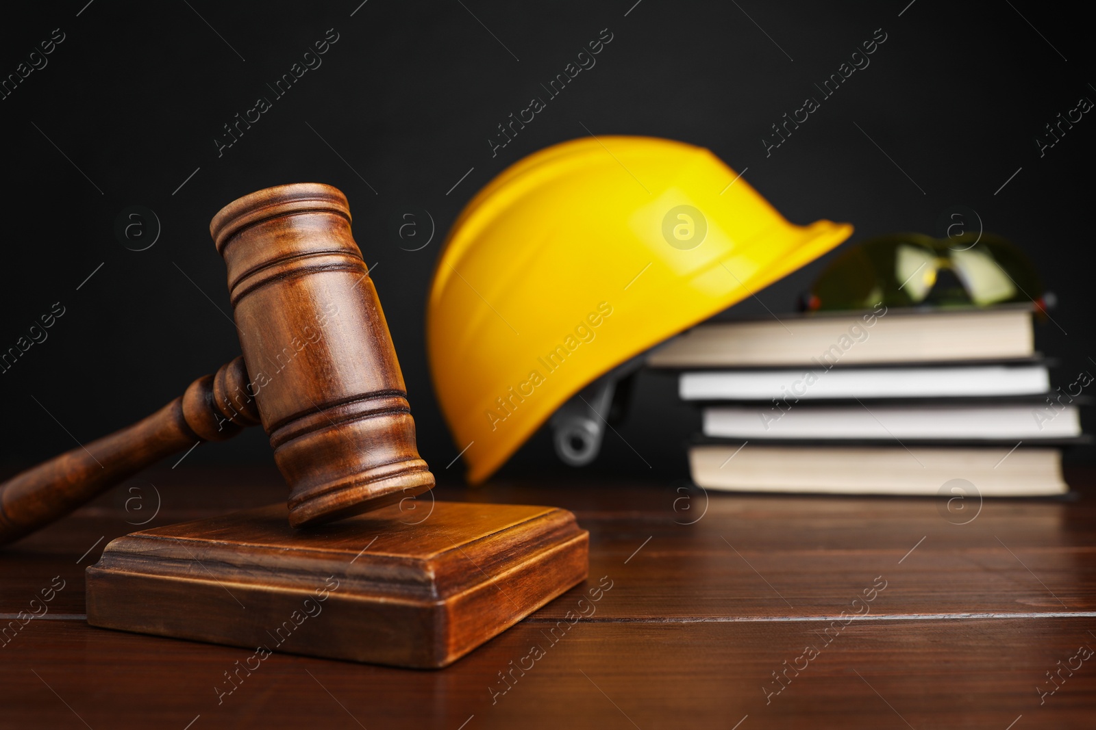 Photo of Accident at work concept. Gavel, books and construction worker's protective gear on wooden table, selective focus