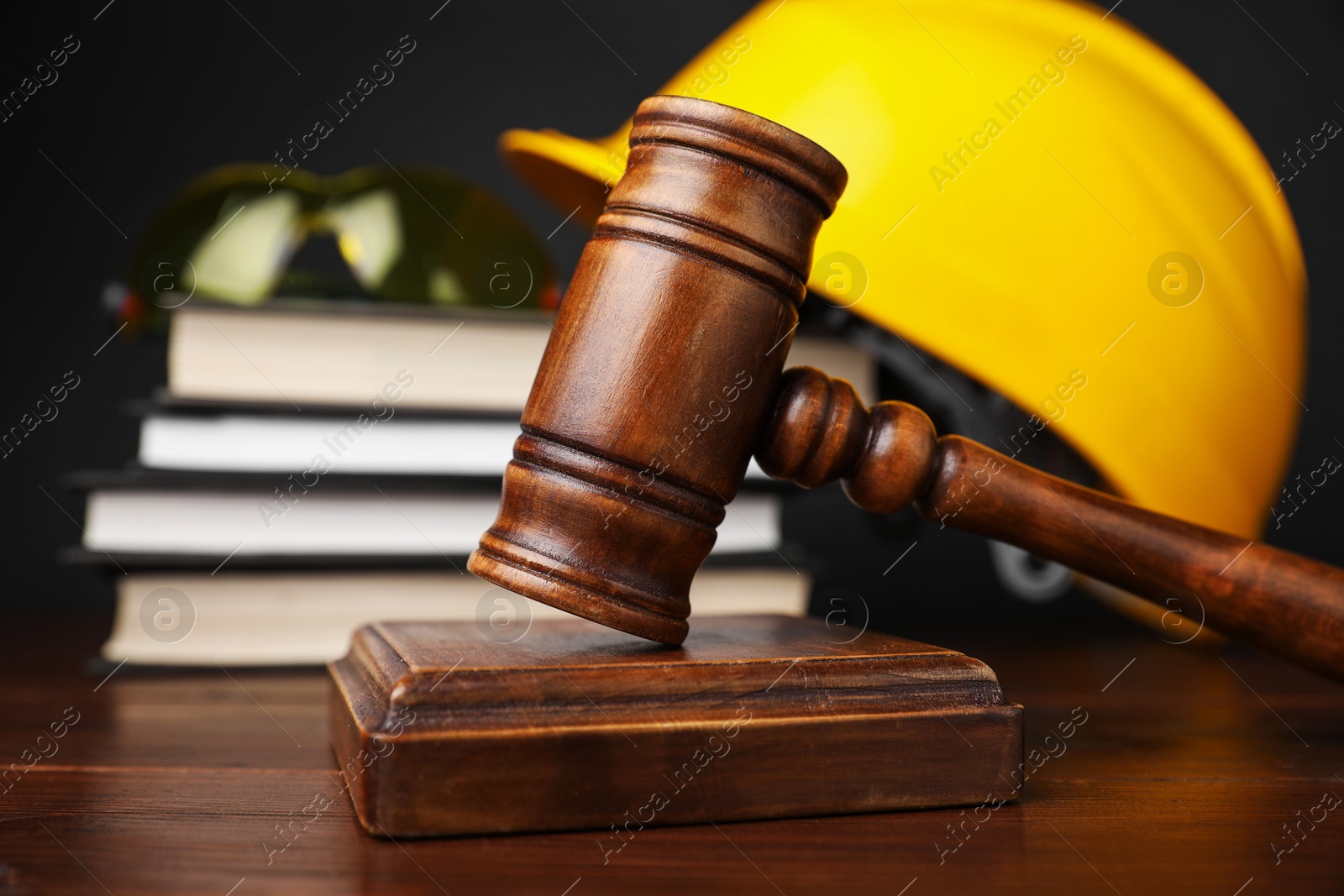 Photo of Accident at work concept. Gavel, books and construction worker's protective gear on wooden table, selective focus