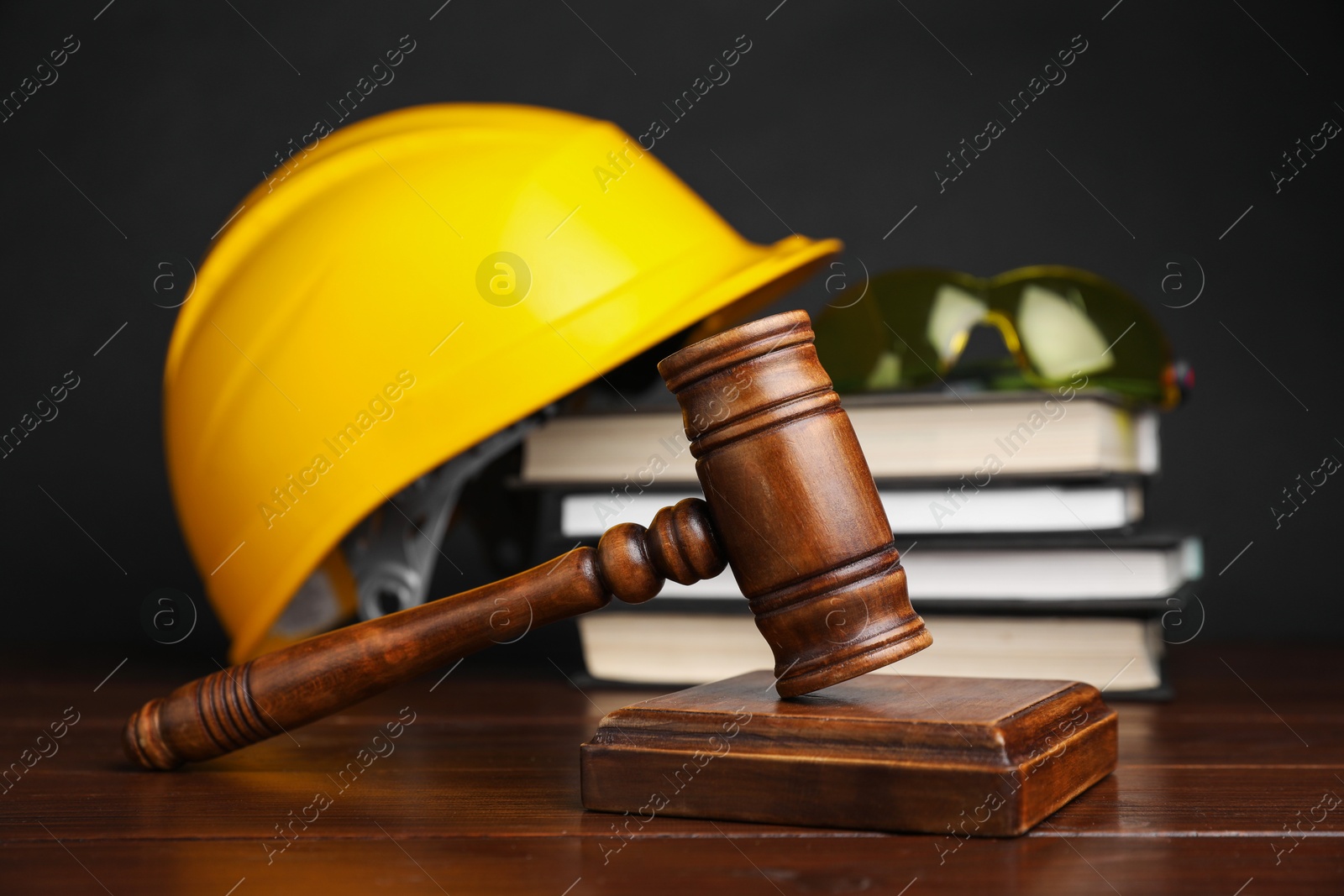 Photo of Accident at work concept. Gavel, books and construction worker's protective gear on wooden table, selective focus