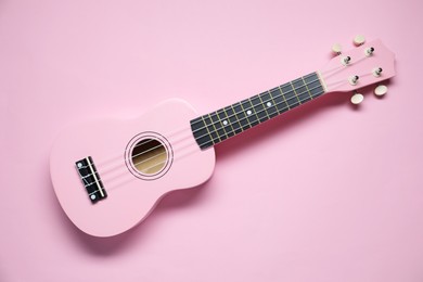 Photo of One ukulele on pink background, top view