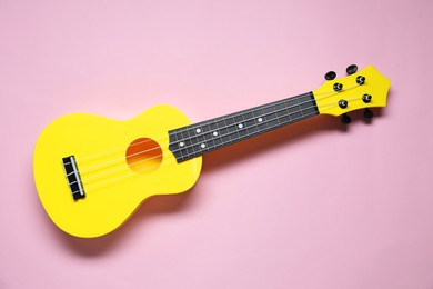 Photo of One ukulele on pink background, top view