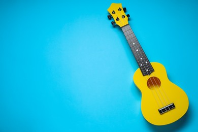 Photo of One ukulele on light blue background, top view. Space for text