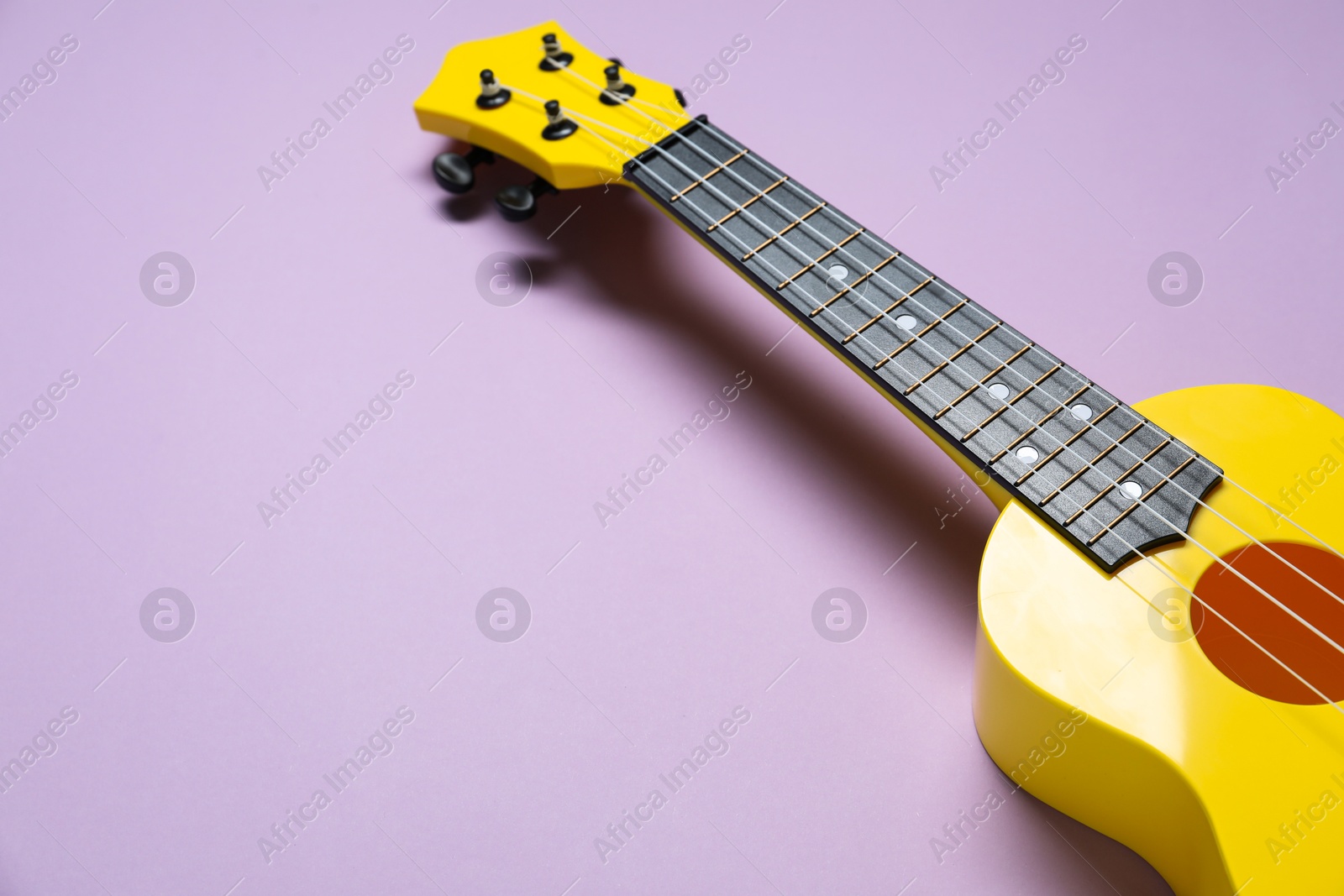 Photo of One ukulele on violet background, space for text