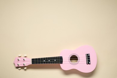 Photo of One ukulele on beige background, top view. Space for text